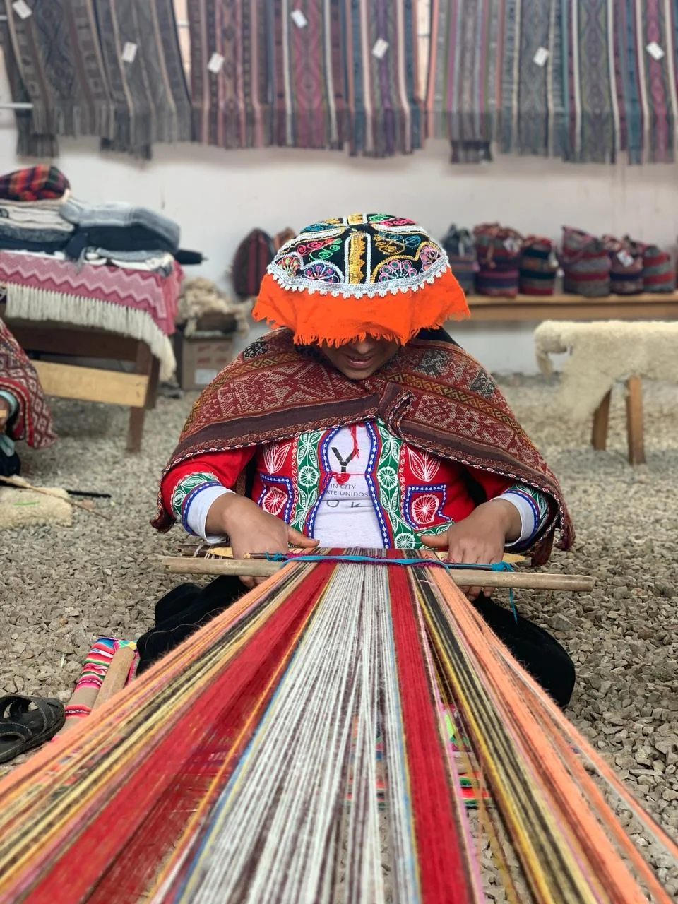 Andean woman artisan weaving on a traditional backstrap loom in traditional dress